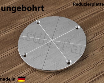 May include: A silver metal reducer plate with six pre-drilled holes. The plate is marked "ungebohrt" and "made in Germany".