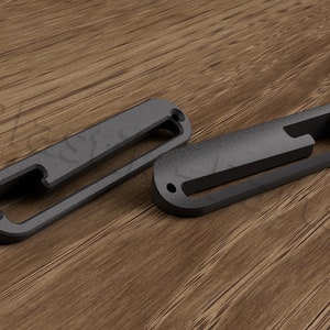 Op de afbeelding: Twee zwarte plastic gitaar-pickup covers met een enkele uitsparing voor een schroef. De covers liggen op een houten oppervlak.