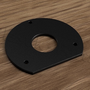 Può includere: Piastra in metallo nero a forma di semicerchio con un foro circolare al centro e quattro fori per viti attorno al bordo.