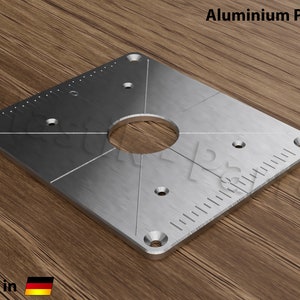 May include: A silver square aluminum plate with a circular hole in the center and a ruler on one side. The plate has several small holes around the edges. The plate is made in Germany.