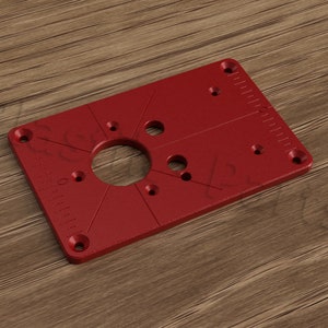 May include: Red plastic router template with a circular cutout and multiple holes for mounting.