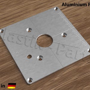 May include: A square aluminium plate with a circular hole in the centre and eight evenly spaced holes around the perimeter. The plate has a ruler marked on one side. The text "Aluminium Platte" is printed in the top right corner of the image.