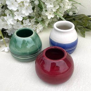 May include: Three small ceramic pots, one green with white stripes, one white with blue stripes, and one red. The pots are round and have a glossy finish.