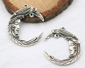 May include: Two silver crescent moon charms with a face in the center of each moon. The moons are detailed with a textured design.