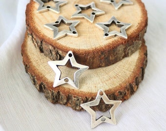 May include: A collection of silver-toned metal star charms with an open center design. The charms are arranged on a wooden surface.