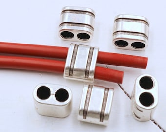 May include: Six silver-toned metal cord end caps with two holes each. The cord end caps have a grooved design and are suitable for use with leather cords.