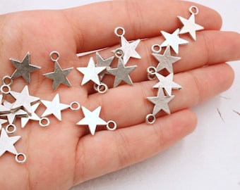 May include: A collection of silver star-shaped charms with jump rings. The charms are scattered on a hand.