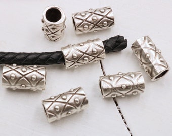 May include: Seven silver metal cord ends with a geometric pattern and raised dots. The cord ends are designed to be used with leather cord.