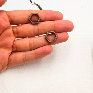 May include: Two small, gold-toned, hexagonal metal charms with a hollow center.