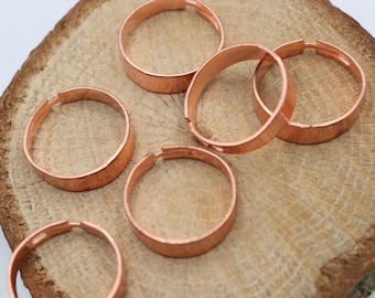 May include: Six copper hoops of varying sizes, arranged on a wooden surface. The hoops are smooth and have a shiny finish.