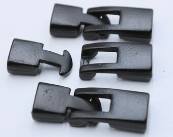 May include: Three black metal clasps for jewellery making. The clasps are rectangular with a small, rectangular opening in the centre. The clasps are designed to be used with a cord or chain.