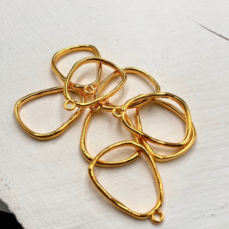 Puede incluir: Cinco piezas en blanco para colgantes de metal dorado con formas irregulares y org&aacute;nicas. Cada pieza en blanco tiene un peque&ntilde;o bucle en la parte superior para sujetar una cadena o un cord&oacute;n.