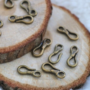 May include: A close-up of a group of antique gold-toned metal clasps or swivels on a wooden surface. The clasps are in various positions, some open and some closed.