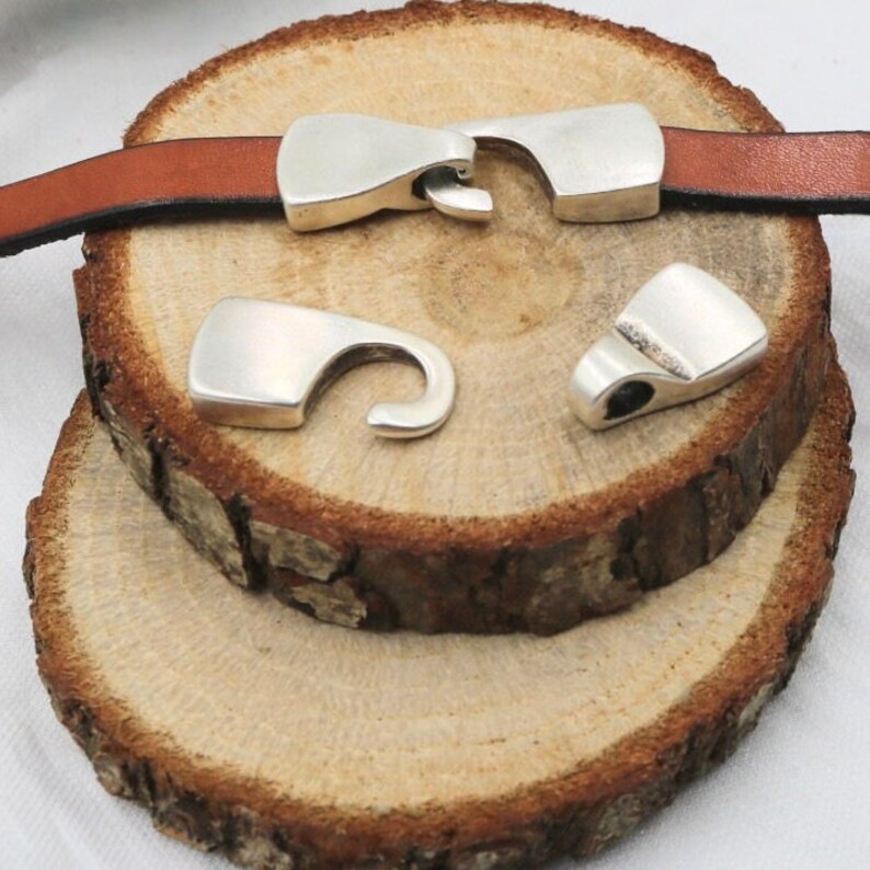 May include: Silver metal clasps for leather straps. The clasps have a hook and loop design.