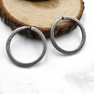 May include: Two silver key rings, each with a circular shape. The key rings are on a white surface.