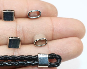 May include: Four silver metal end caps for leather cord or rope. The end caps are in various shapes and sizes. One end cap is attached to a black leather cord.