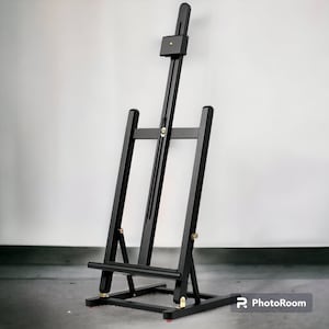 Op de afbeelding: Een zwarte houten ezel met verstelbare hoogte en een kantelbaar bovenblad. De ezel is ontworpen om kunstwerken of foto's te presenteren.