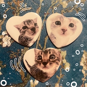 May include: Three heart-shaped decorative magnets featuring close-up images of adorable kittens. Each magnet showcases a different kitten with unique markings and expressions. The magnets are white with a glossy finish, perfect for refrigerators or magnetic surfaces.