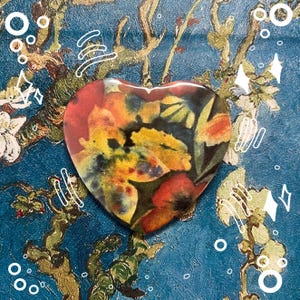 May include: A heart-shaped resin paperweight with a colorful floral design. The design features a mix of red, yellow, blue, and green hues.