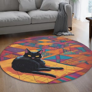May include: A round area rug featuring a stylized black cat with yellow eyes, resting on a geometric pattern of orange, yellow, blue, and purple shapes. The rug is placed on a wooden floor.