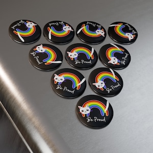 May include: Nine black and white button badges featuring a rainbow and a white cat. Each badge reads "Be Proud" in white text.