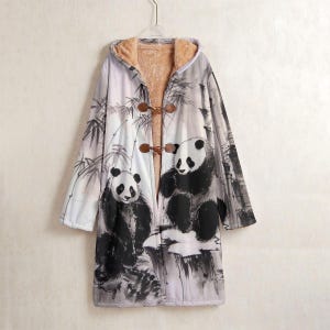May include: A long hooded coat featuring a panda bear design in black and white. The coat has a light brown, fuzzy interior and wooden toggle closures. The outer layer depicts pandas and bamboo in a watercolor style.