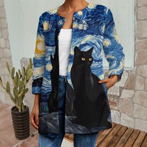 May include: A long-sleeved, open-front coat featuring a print of Van Gogh's "Starry Night" with a black cat. The coat's design includes a blue and yellow swirling sky and a black cat with yellow eyes. The coat has a relaxed fit and pockets.