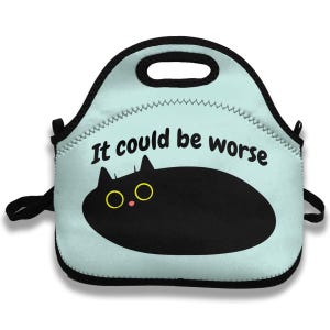 Può includere: Una borsa per il pranzo azzurra con finiture e manico neri. La borsa presenta un'illustrazione di un gatto nero con occhi gialli e la scritta "It could be worse" in nero.