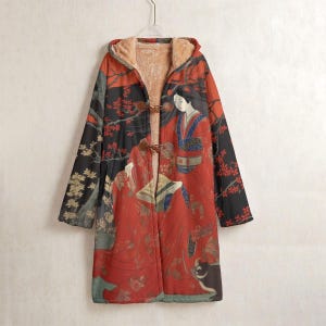 May include: A long, hooded coat featuring a Japanese art print. The coat has a red and black design with a woman in a kimono. It has a toggle closure and a soft, tan-colored lining. The coat is hanging on a hanger.