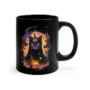 May include: Black ceramic coffee mug with a black cat wearing a wizard hat and a third eye. The cat is surrounded by a purple and orange moon and stars. The text "The Magicat" is printed below the cat.