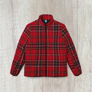 Könnte beinhalten: Eine rot-schwarze karierte Jacke mit Reißverschluss. Die Jacke hat einen Stehkragen und lange Ärmel.