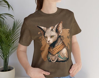 May include: A brown t-shirt featuring a graphic of a Sphynx cat wearing a gold and blue patterned scarf. The cat has green eyes and a serious expression.