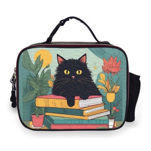 May include: A black cat with yellow eyes rests on a stack of books, featured on a lunch bag. The bag has a teal background with a sun, plants, and flowers. The bag has a black handle, zipper, and a side mesh pocket.