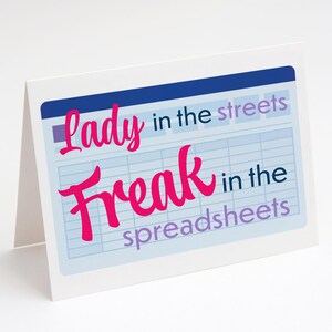 May include: A white greeting card with the text "Lady in the streets, Freak in the spreadsheets" in pink and purple. The text is set against a light blue spreadsheet background.