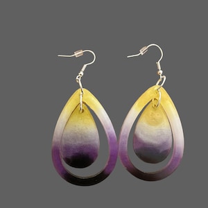 May include: A pair of dangle earrings with a yellow, white, and purple ombre design. The earrings are made of two teardrop shapes, one inside the other.