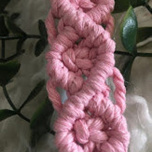 May include: Pink macrame cord woven into a decorative pattern, creating a series of small circles.