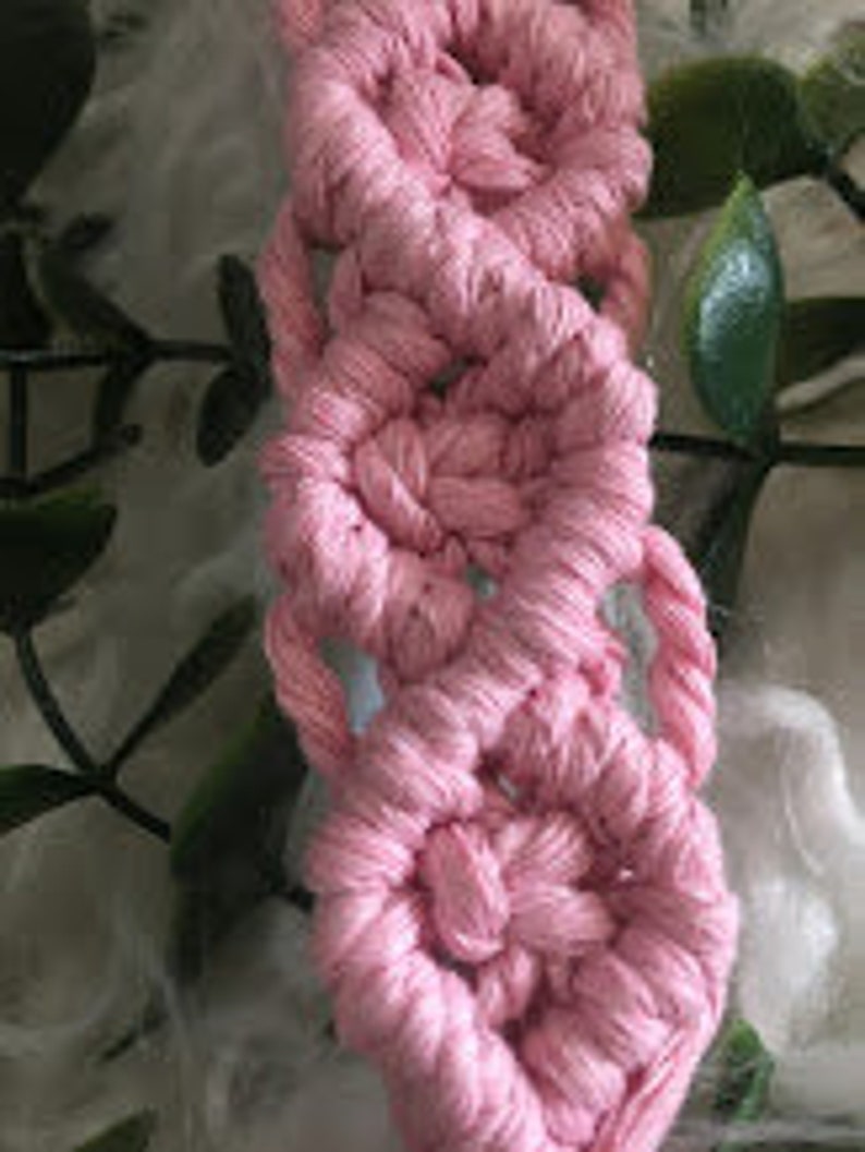 May include: Pink macrame cord woven into a decorative pattern, creating a series of small circles.