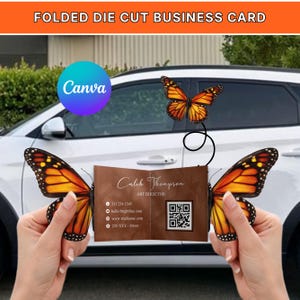 Peut inclure: Une carte de visite pliée et découpée avec un fond marron, portant le nom de "Caleb Thompson, Art Director". La carte est maintenue ouverte avec des ailes de papillon. La carte comprend des coordonnées et un code QR. L'image comprend également le mot "Canva".