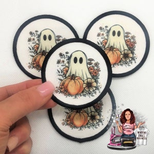 May include: Round patches with a Halloween theme. Each patch features a friendly ghost, a pumpkin, and floral accents in orange, cream, and brown. The patches have a black border and are displayed against a white background.