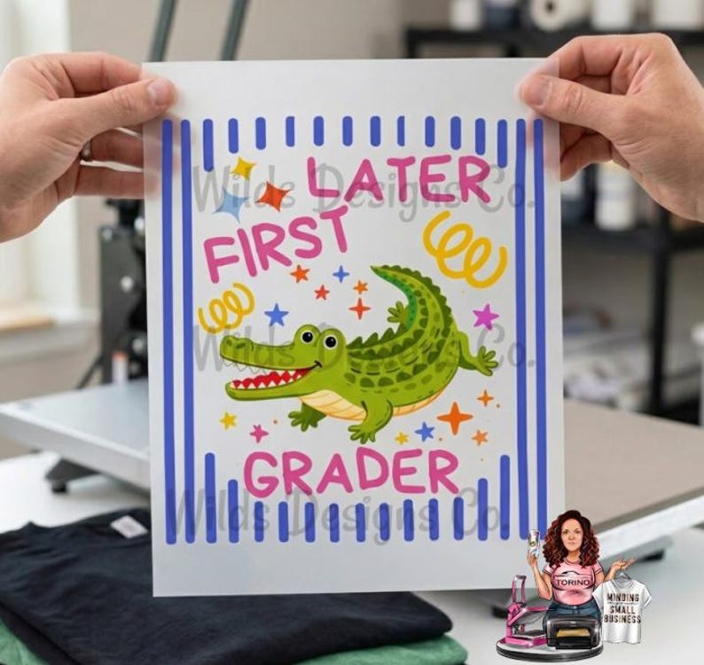 Pu&ograve; includere: Un foglio di trasferimento bianco con un design colorato con un alligatore verde, stelle e le parole "Later First Grader". Il design &egrave; incorniciato da strisce verticali blu.