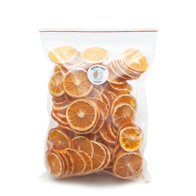 May include: A clear plastic bag filled with dried orange slices. The bag has a label that says "Cocktail Candy Dehydrated Oranges".