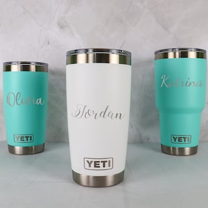 May include: Three Yeti tumblers with personalized names: Olivia, Jordan, and Katrina. The tumblers are in turquoise and white with silver lids and bases.