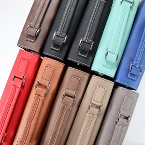 May include: A stack of ten different coloured leather zippered cases with silver buckles and handles.