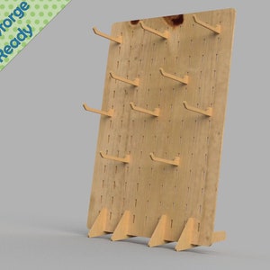 May include: A wooden pegboard with hooks for hanging items. The pegboard has a light wood finish and is standing on four small legs.