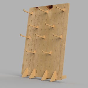 Könnte beinhalten: Ein helles Holz-Displayboard mit einem Raster aus vertikalen Schlitzen und mehreren abnehmbaren Holzhaken. Die rechteckige Platte wird von vier dreieckigen Holzfüßen an der Basis gestützt, wodurch sie aufrecht auf einer Fläche stehen kann.