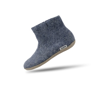 May include: A slate blue felt ankle boot with a high-top silhouette and a light beige sole. The boot features a small white rectangular fabric tag on the side with the text woolly felt printed in black, and visible stitching along the sole edge.