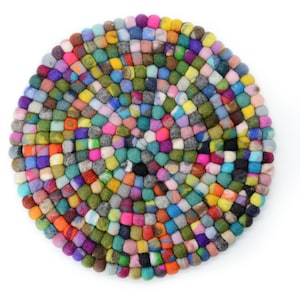 Op de afbeelding: Een ronde, kleurrijke vilten onderzetter met een mozaïekpatroon. De onderzetter is gemaakt van kleine, dicht opeengepakte vilten ballen in verschillende kleuren, waaronder roze, groen, blauw, geel en paars. Op een witte achtergrond.