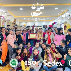 May include: A large group of diverse individuals posing together in a retail space, with various certification logos overlaid including Fairtrade, GMP, ISO, Sedex, and CE, alongside text reading 100% ORIGINAL, ETHICALLY MADE, and HANDMADE WITH LOVE.