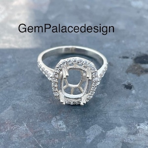 May include: A silver ring setting with a pave diamond halo and a center stone setting. The ring is designed for a cushion-shaped gemstone.