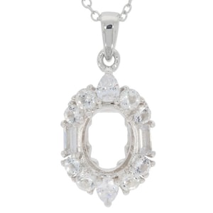 Puede incluir: Pendiente de plata con un engaste ovalado transparente rodeado de piedras transparentes más pequeñas. El pendiente está unido a una cadena de plata.
